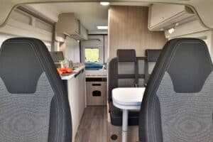 Hoge kwaliteit camperinterieur met moderne keuken en comfortabele zithoek voor avontuurlijke reizen.
